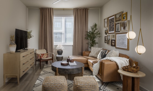 a living room with couches and tables and a tv with art on the wall and a window